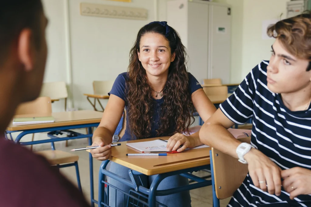 Elever sidder sammen i et klasseværelse og deltager i gruppearbejde.